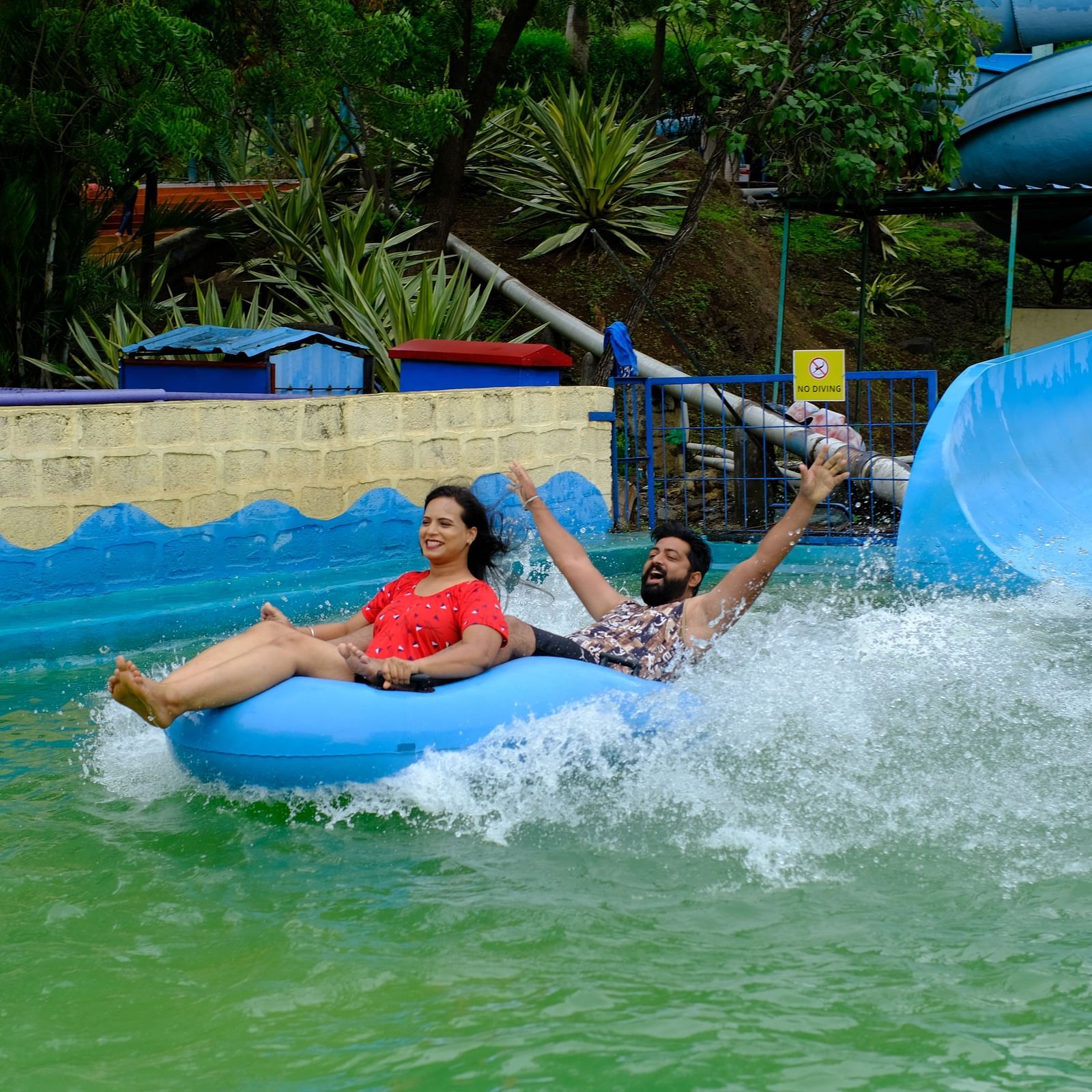 couple having fun on a water slide in a rubber raft at an adventure water park | Diamond Parks, Pune 
