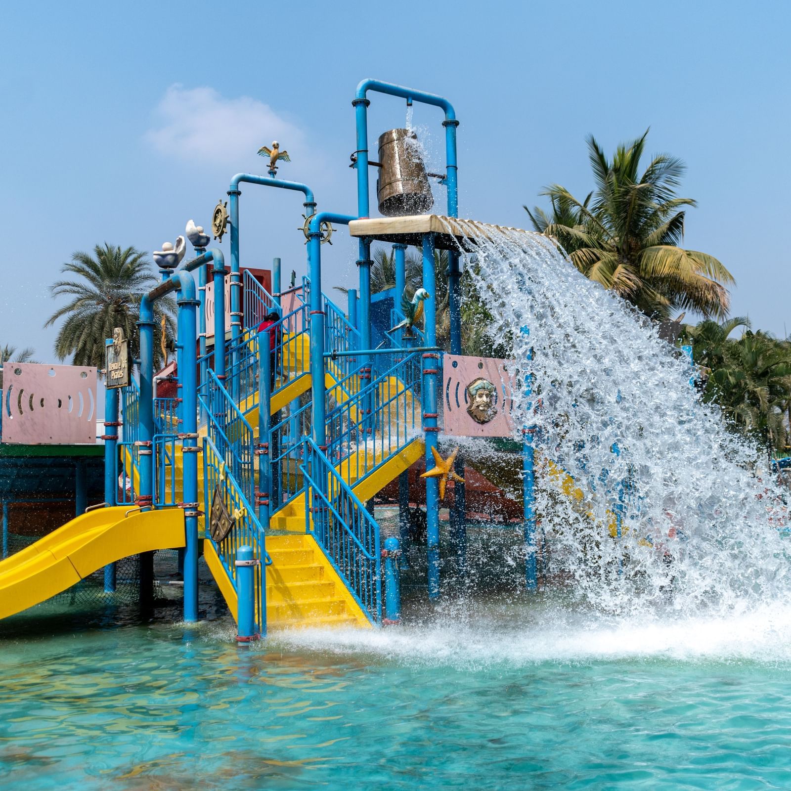 Children playing in a colourful water park with slides and large splash buckets, sunny day | Diamond Parks, Pune