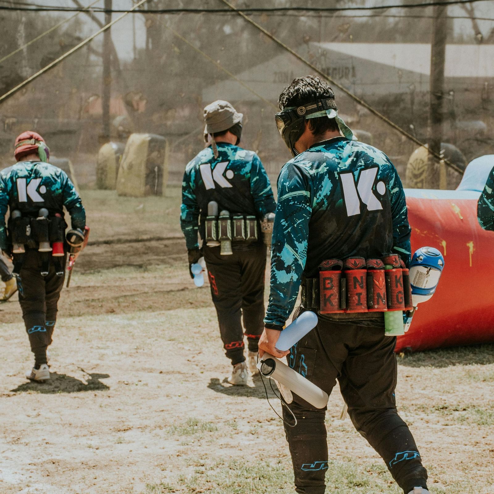 A group of people walking on the paintball turf in full gear