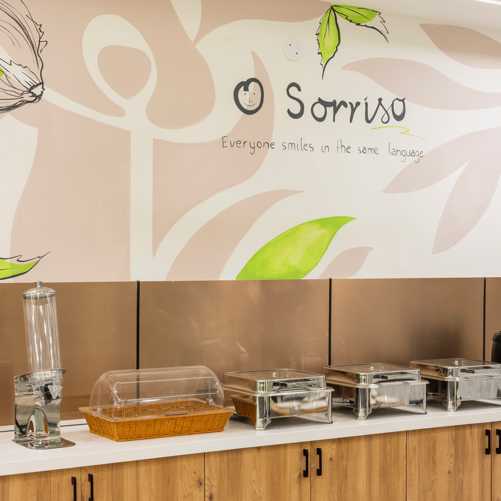 A buffet area with food warmers and a wall graphic at Elysium Studio Suites, Madhapur, shows food service equipment.