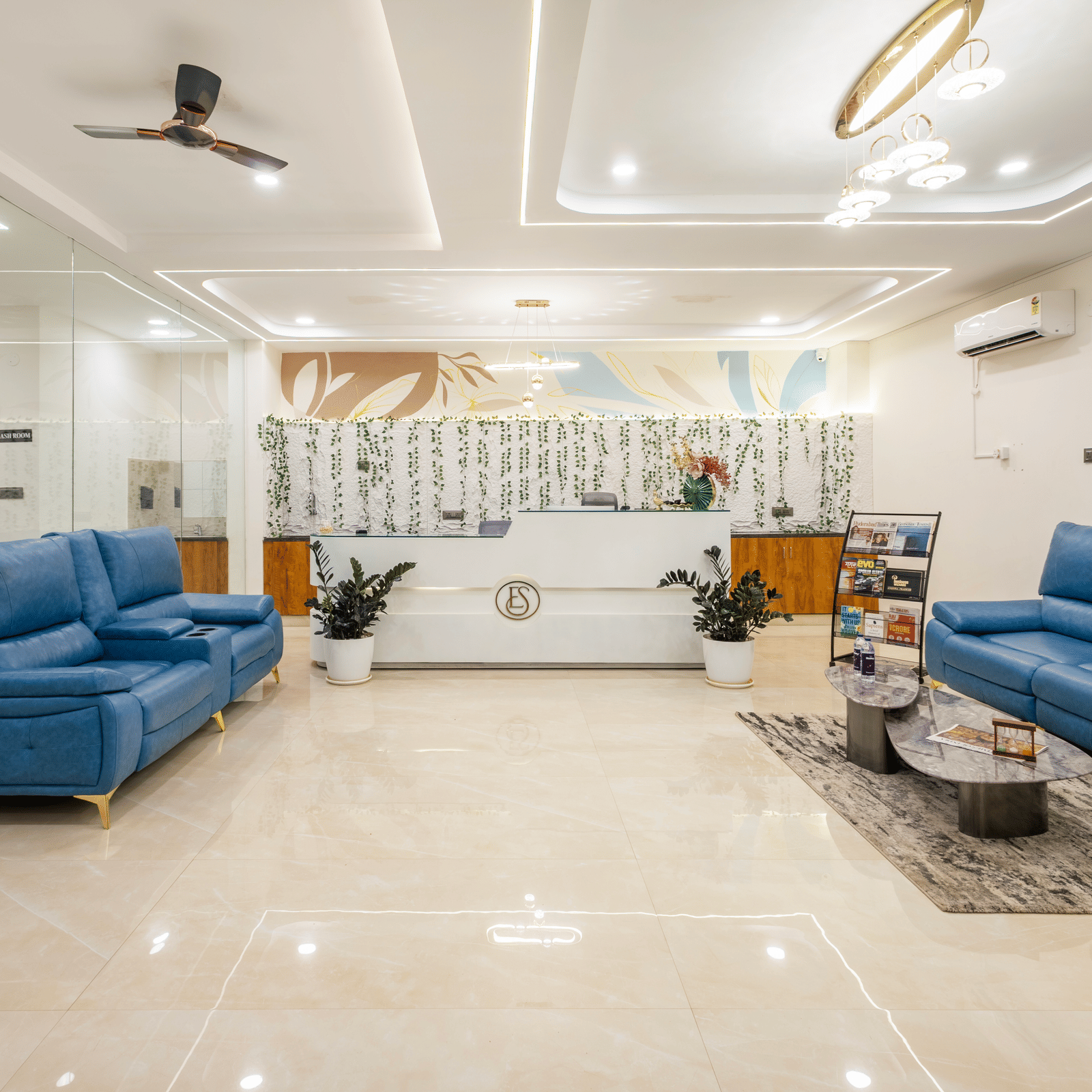 A living room at Elysium Studio Suites, Madhapur, contains blue sofas and light fixtures on the ceiling.