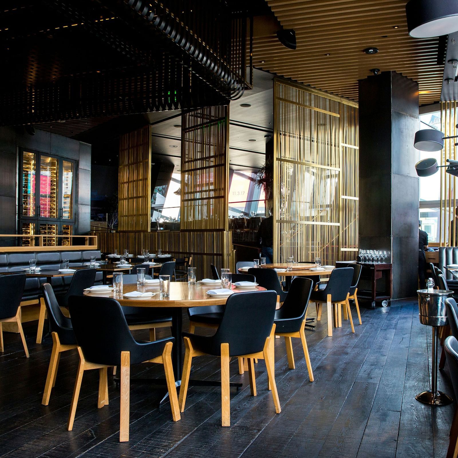 a dining area with dark coloured wooden flooring with black cushioned chairs