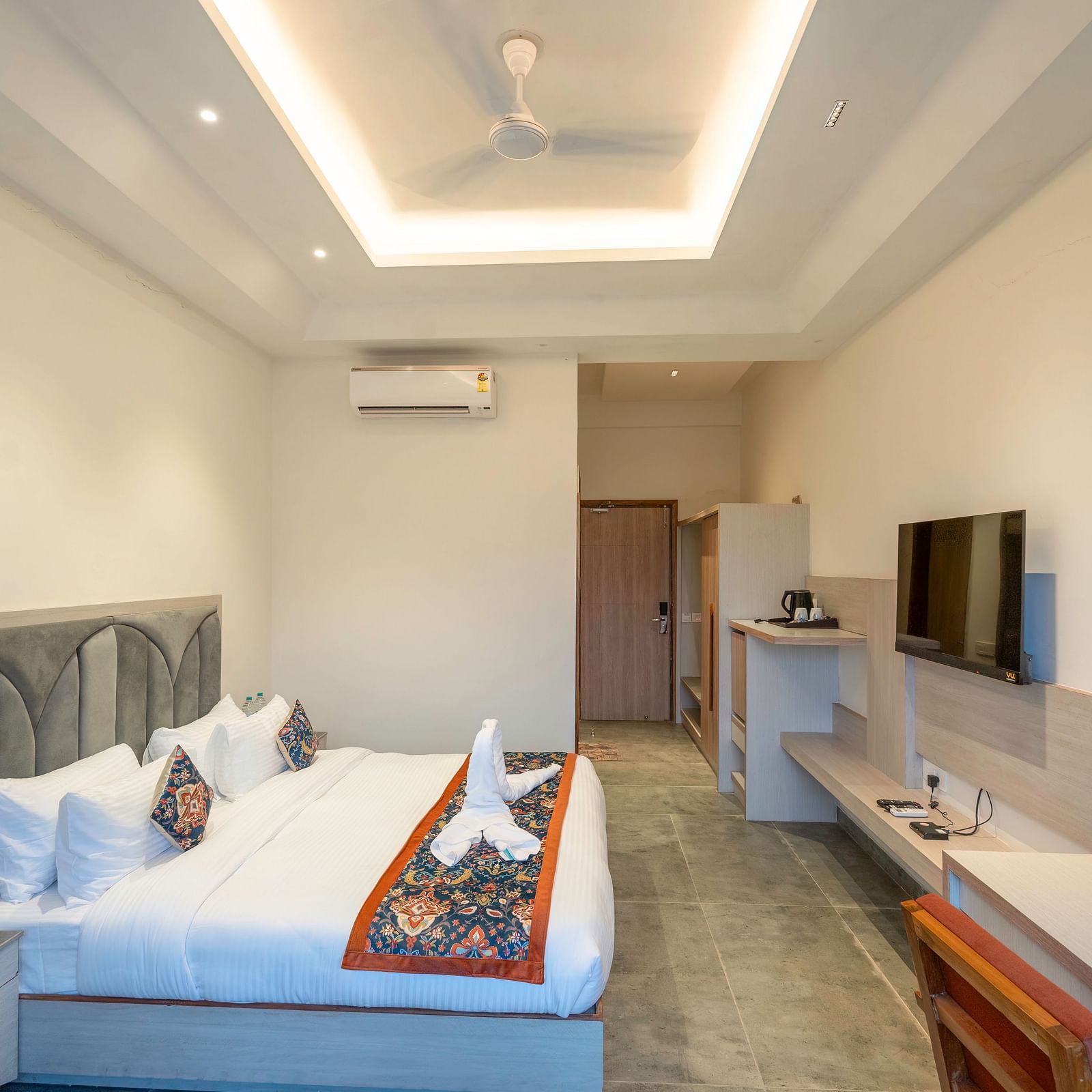 A bright and airy hotel room with a comfortable king-size bed, a flat-screen TV, and a kitchenette, perfect for a relaxing stay.