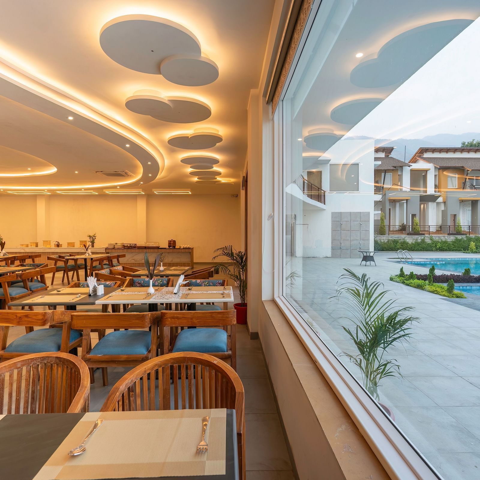 A modern dining room with a view of the resort grounds through large windows.