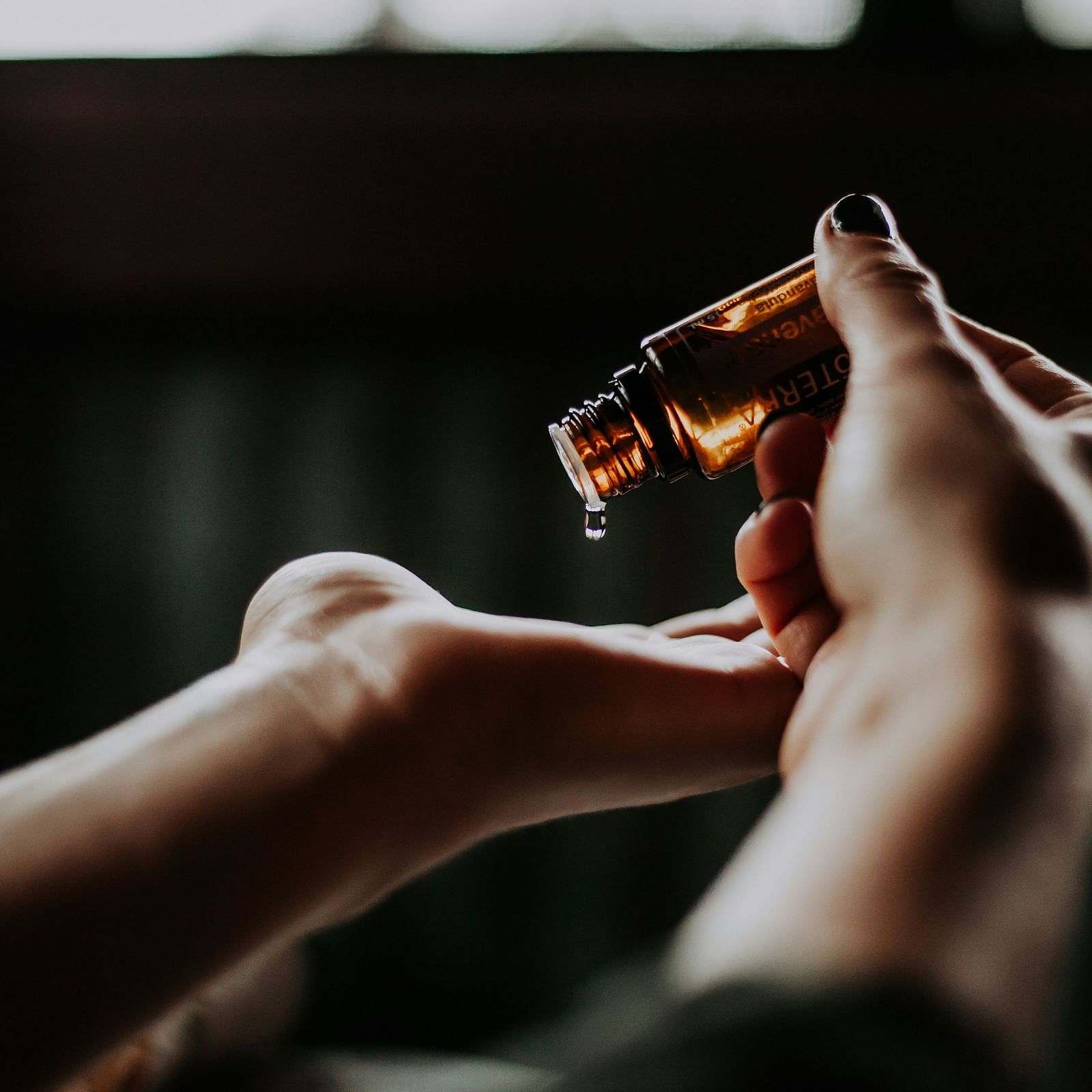A woman pouring essential oil on her palm.