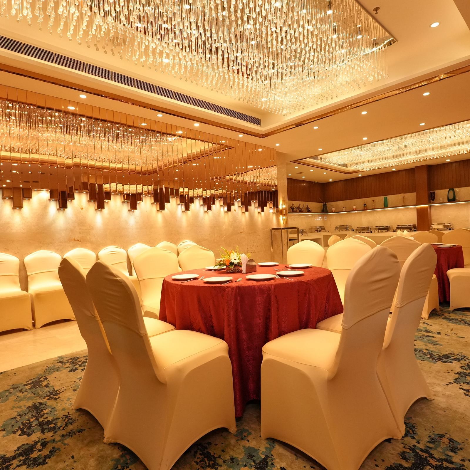 Spacious banquet room with chandelier and seating arrangement at Grand Plaza Lords Inn Jammu.