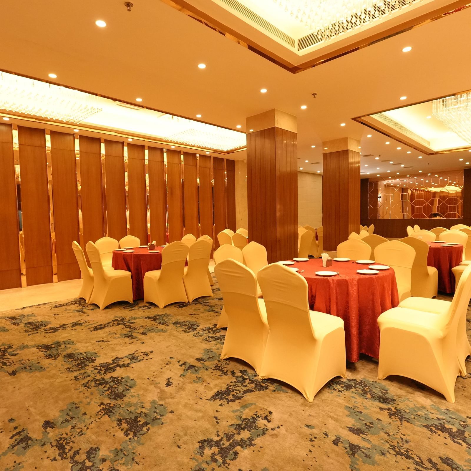 Elegant banquet hall with round tables and beige chairs at Grand Plaza Lords Inn Jammu.