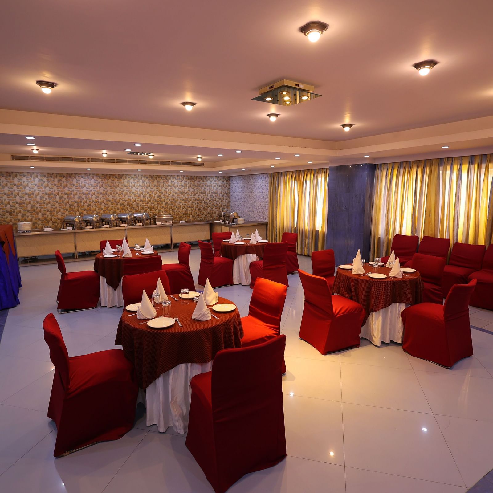 Overview Image of Dewaane-e-khas hall of Hotel Amar with red chairs and cluster seating arrangement 