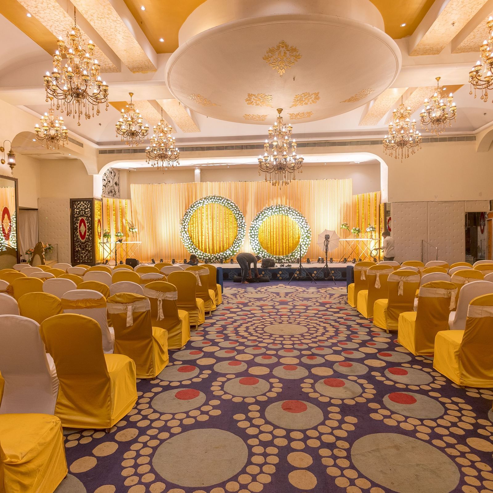 A ballroom setting with rows of chairs and patterned carpeting at Hotel Ashok Nagpur.