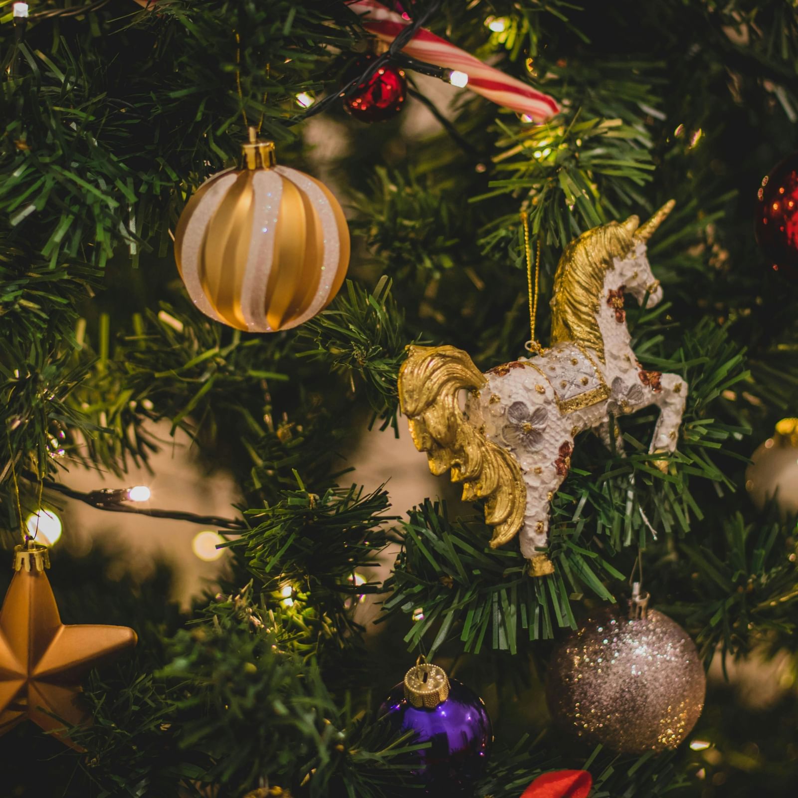 Christmas tree decorated with several items like horse, bells, stars, balls, fairy lights, etc.