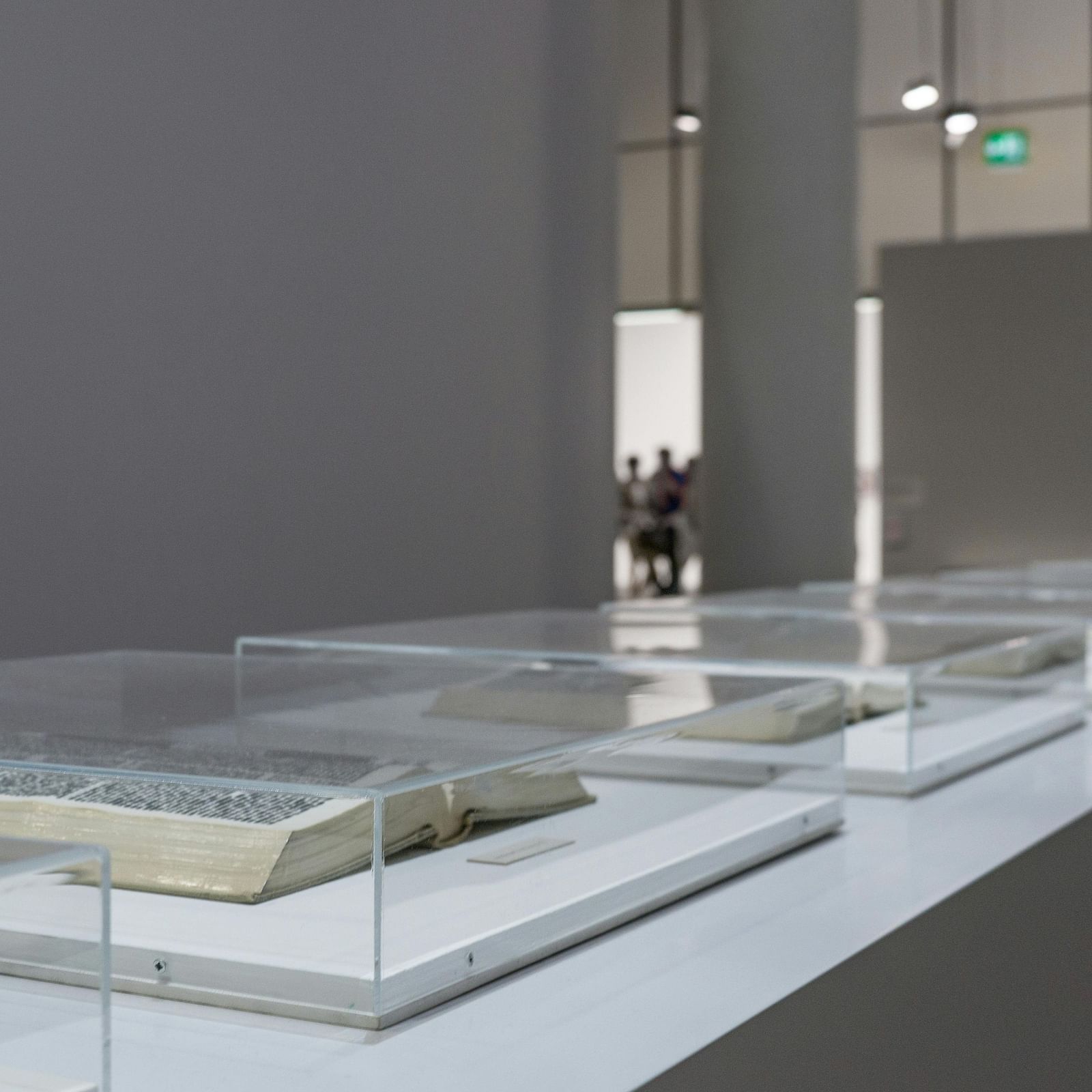 few open books kept for display in a museum covered in transparent cases