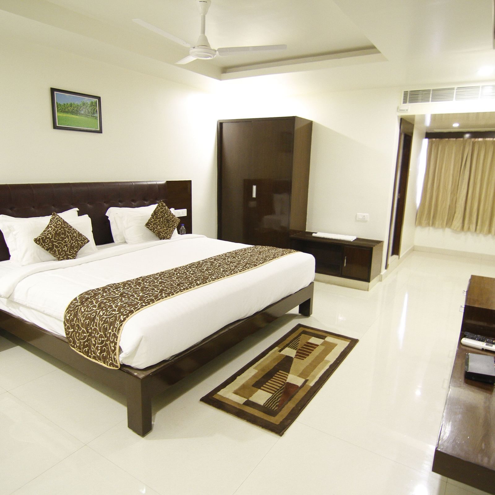 Elite Room with room with bed, wardrobe and television in front at Jyothi hall with seats arranged and lights on the ceiling at Hotel Green Apple