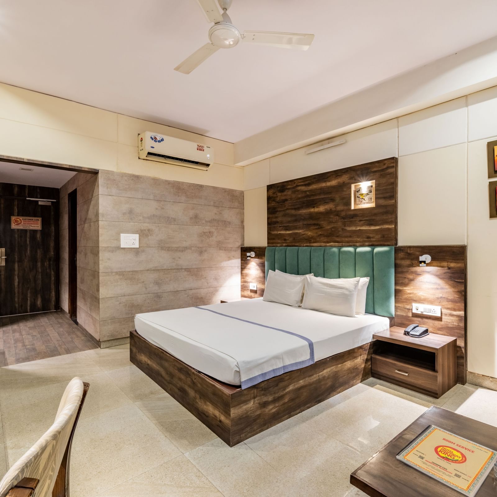 Extended view of the Maharaja Deluxe Room at Hotel Highway King, Behror, furnished with a double bed, air-conditioning, a work desk and seating area for two.