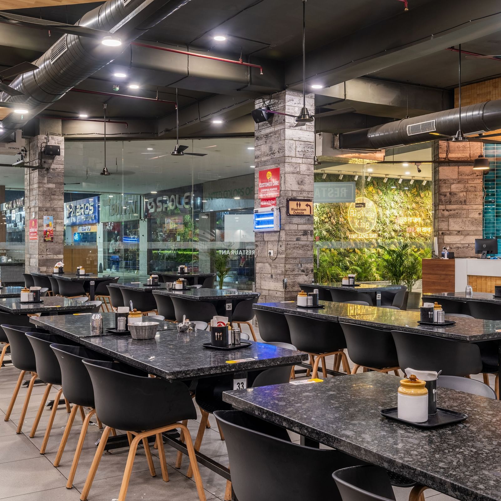 Cosy dining space with black tables and natural lighting at Hotel Highway King, Bilaspur.