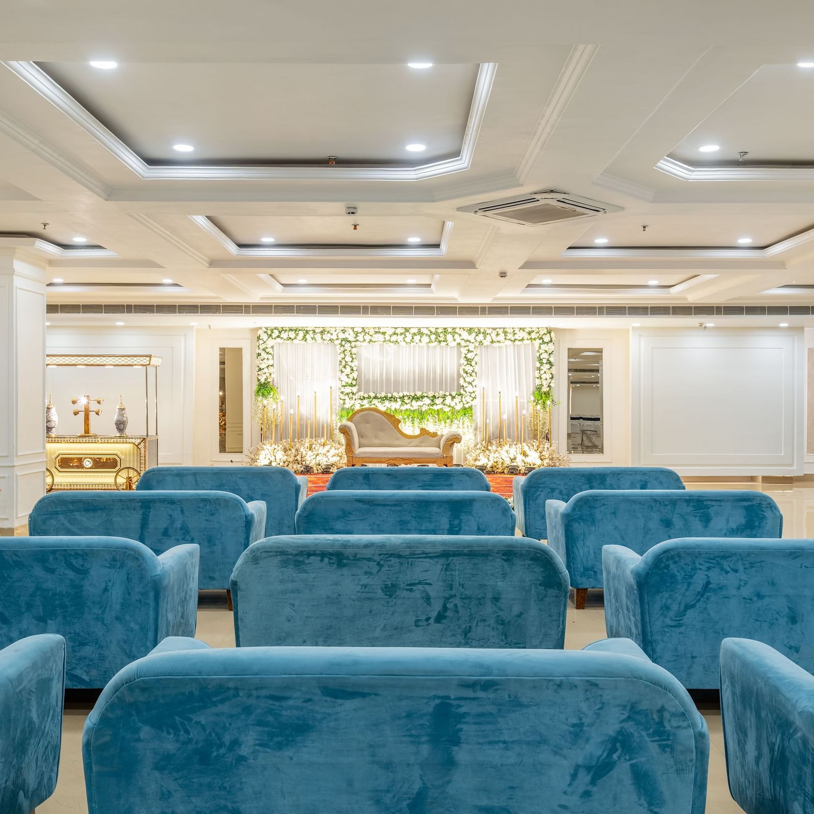 Comfortable blue lounge seating in a large, elegant banquet hall at Hotel Highway King, Bilaspur.