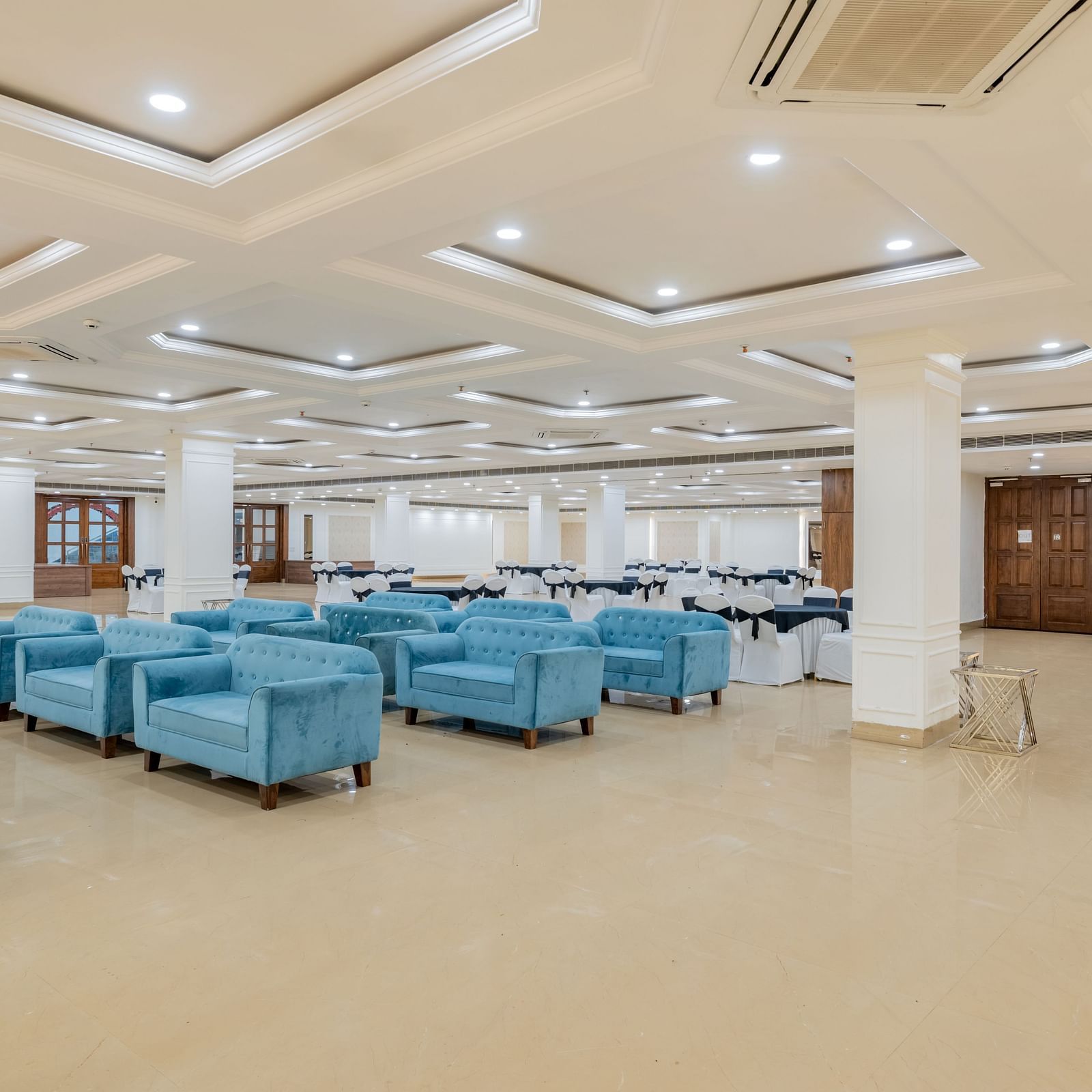 Banquet space featuring multiple blue sofa sets arranged in a modern layout at Hotel Highway King, Bilaspur.