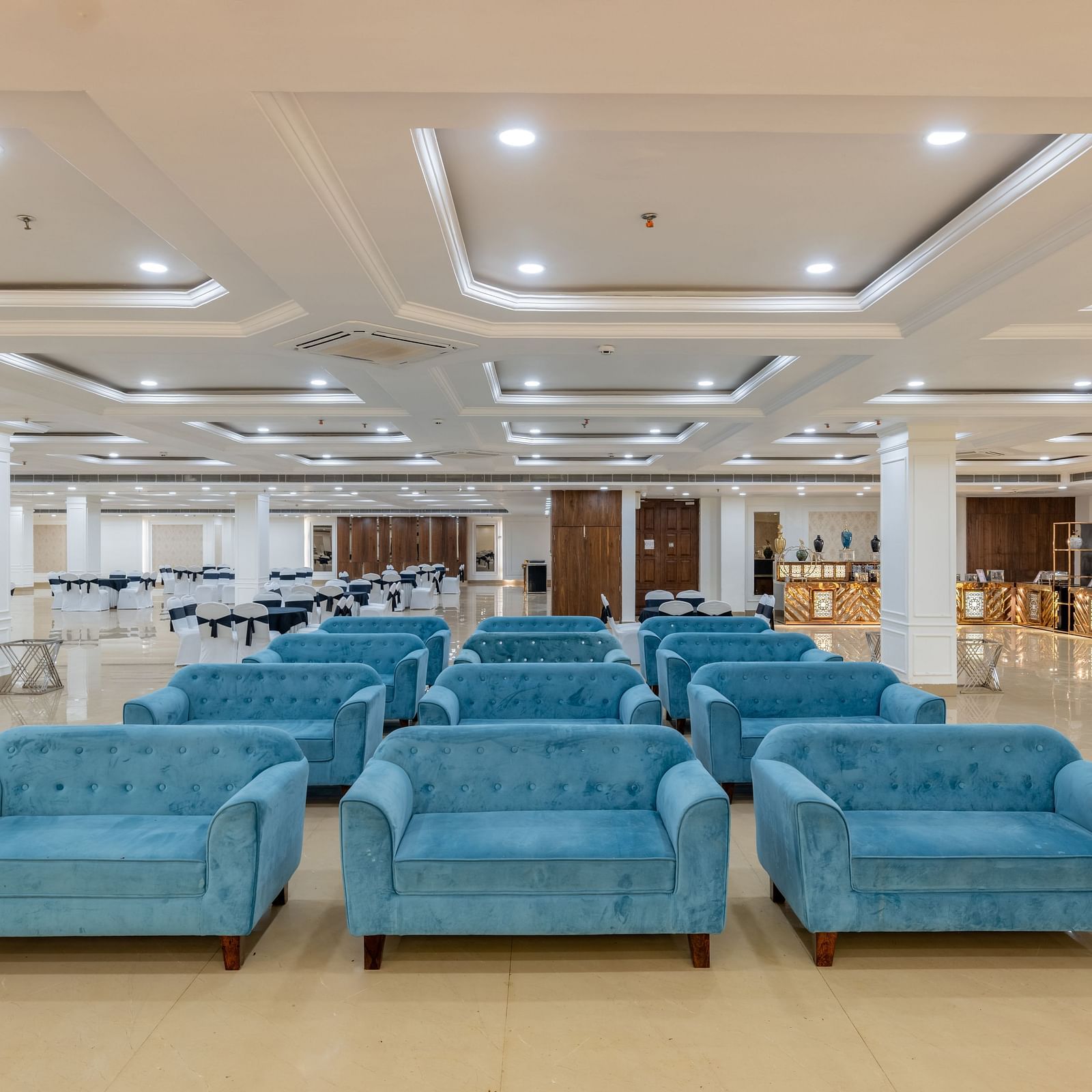 Well-organised hall with stylish ceiling design and blue sofas at Hotel Highway King, Bilaspur.