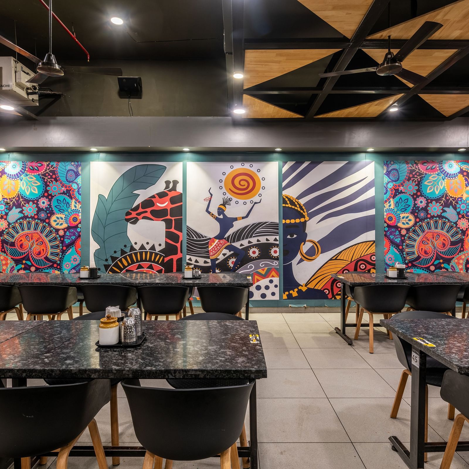 Colourful wall mural with vibrant artwork and neatly arranged tables at Hotel Highway King, Bilaspur.