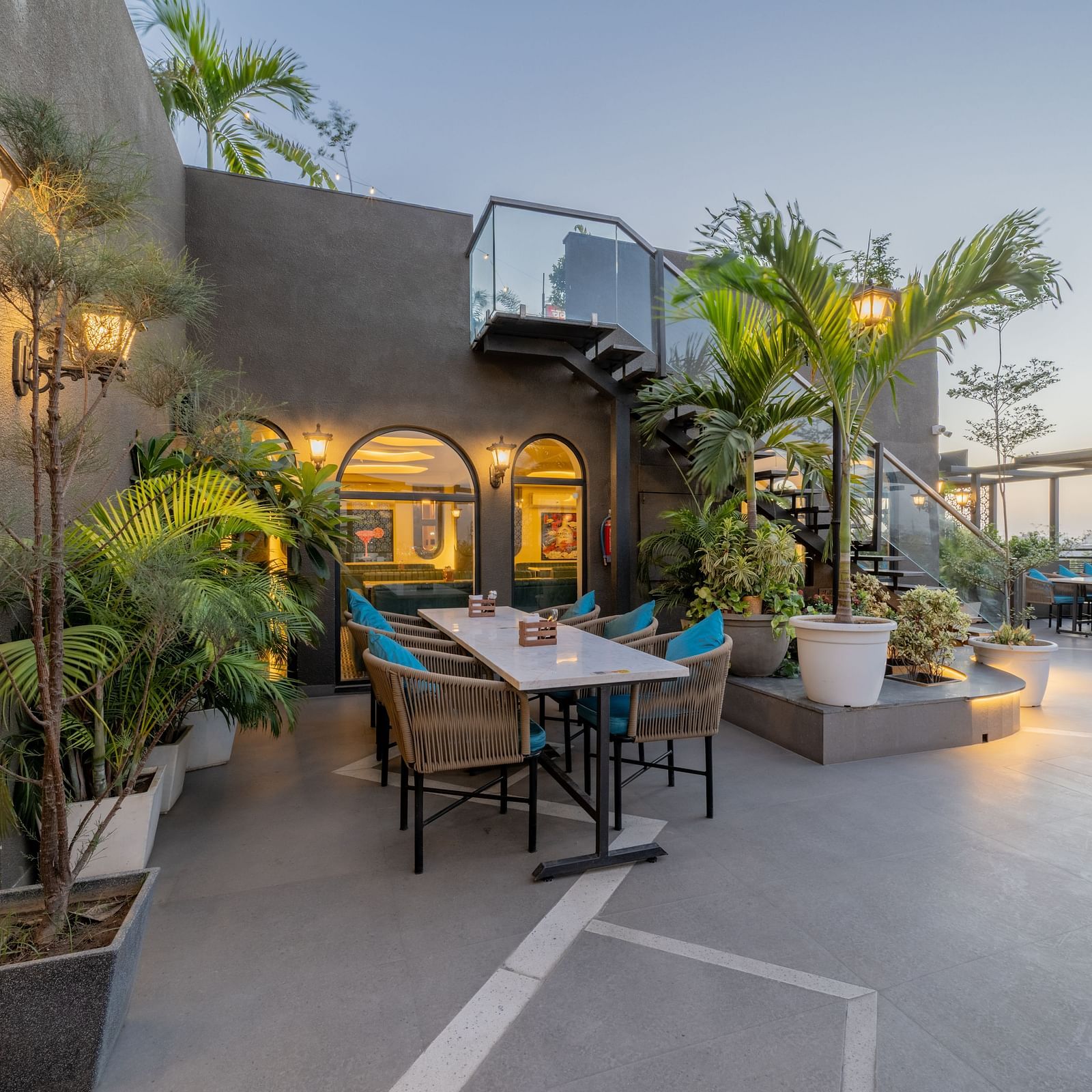 Cosy outdoor seating near arched window and tropical plants at Hotel Highway King, Jaipur.