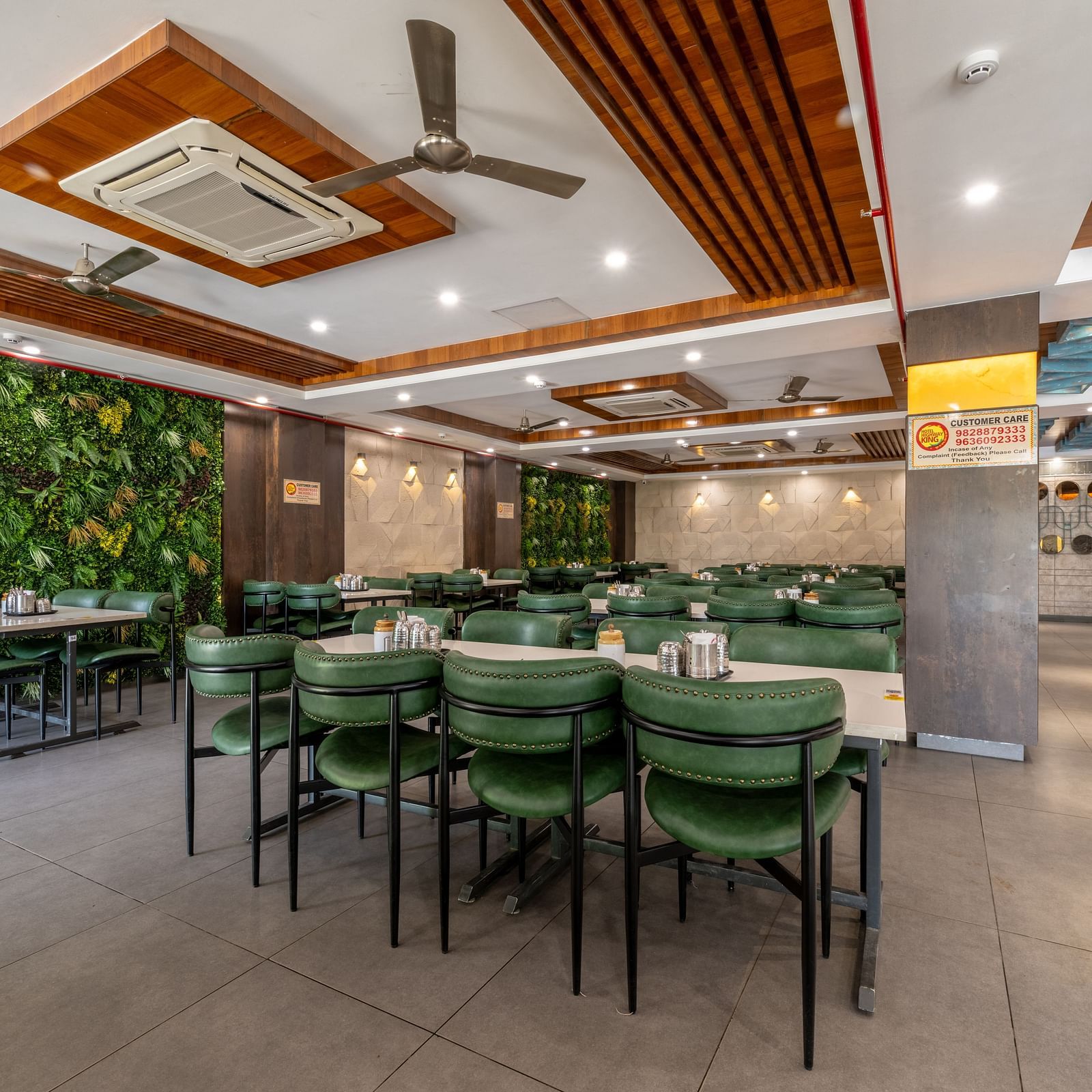 Restaurant interior with tile flooring, dining tables, and wall-mounted green plants at Hotel Highway King, Jaipur.
