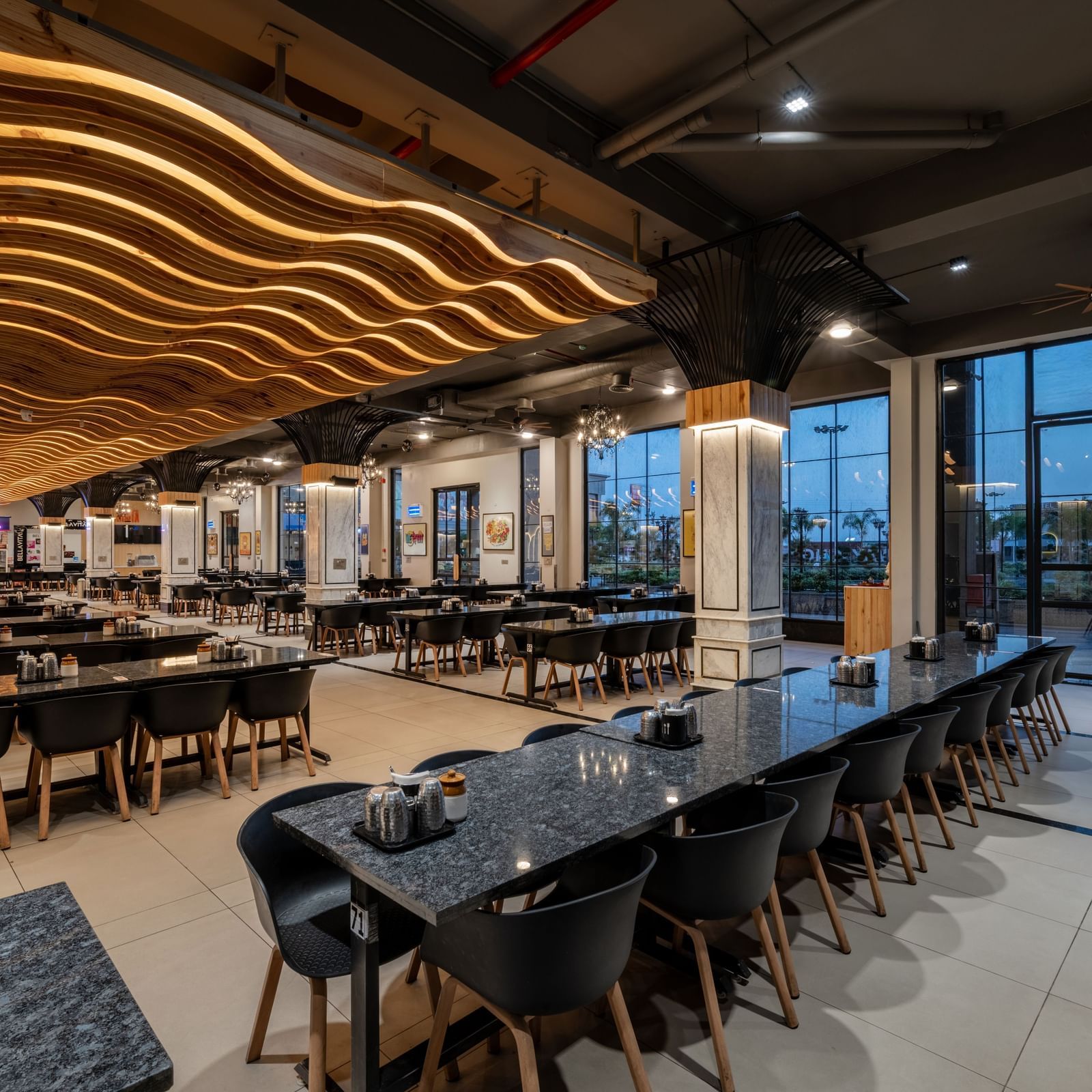 Restaurant section with long dining tables and overhead lighting at Hotel Highway King, Kishangarh.
