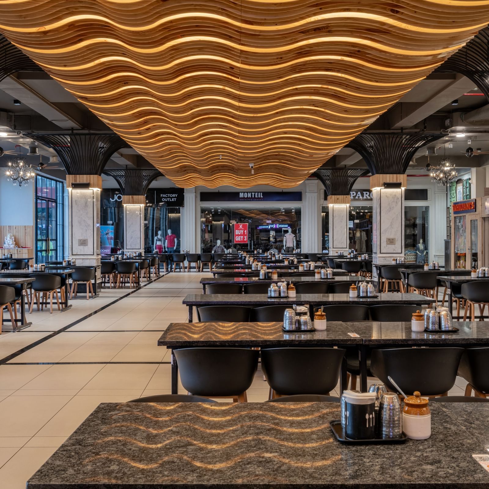 The spacious dining hall at Hotel Highway King, Kishangarh, with its unique wavy ceiling and multiple tables set for guests.