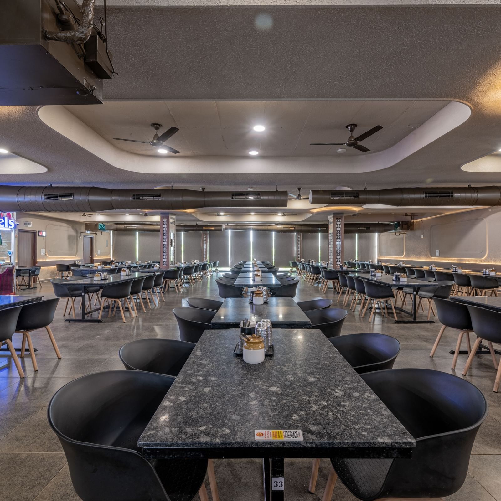A close-up view of a table with chairs arranged neatly around it, with warm lighting, at Hotel Highway King, Neelka.