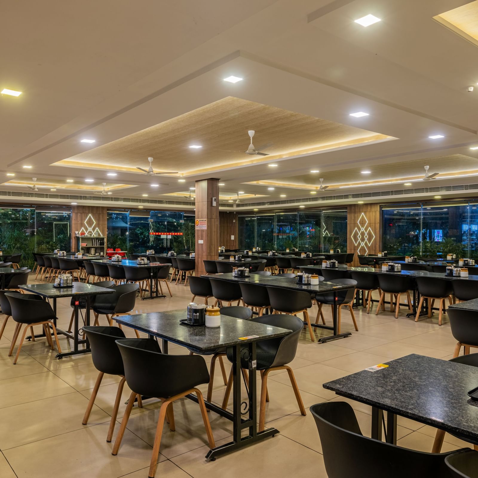 A closer perspective of the well-arranged dining area at Hotel Highway King Shahpura, showing many tables.