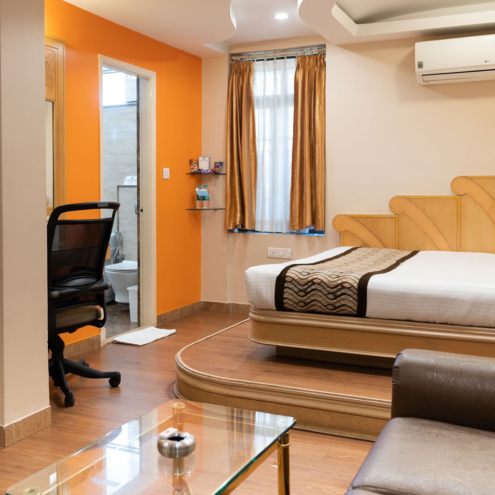 The suite at Hotel Pai Viceroy Jayanagar featuring warm interiors, a queen sized bed and a couch