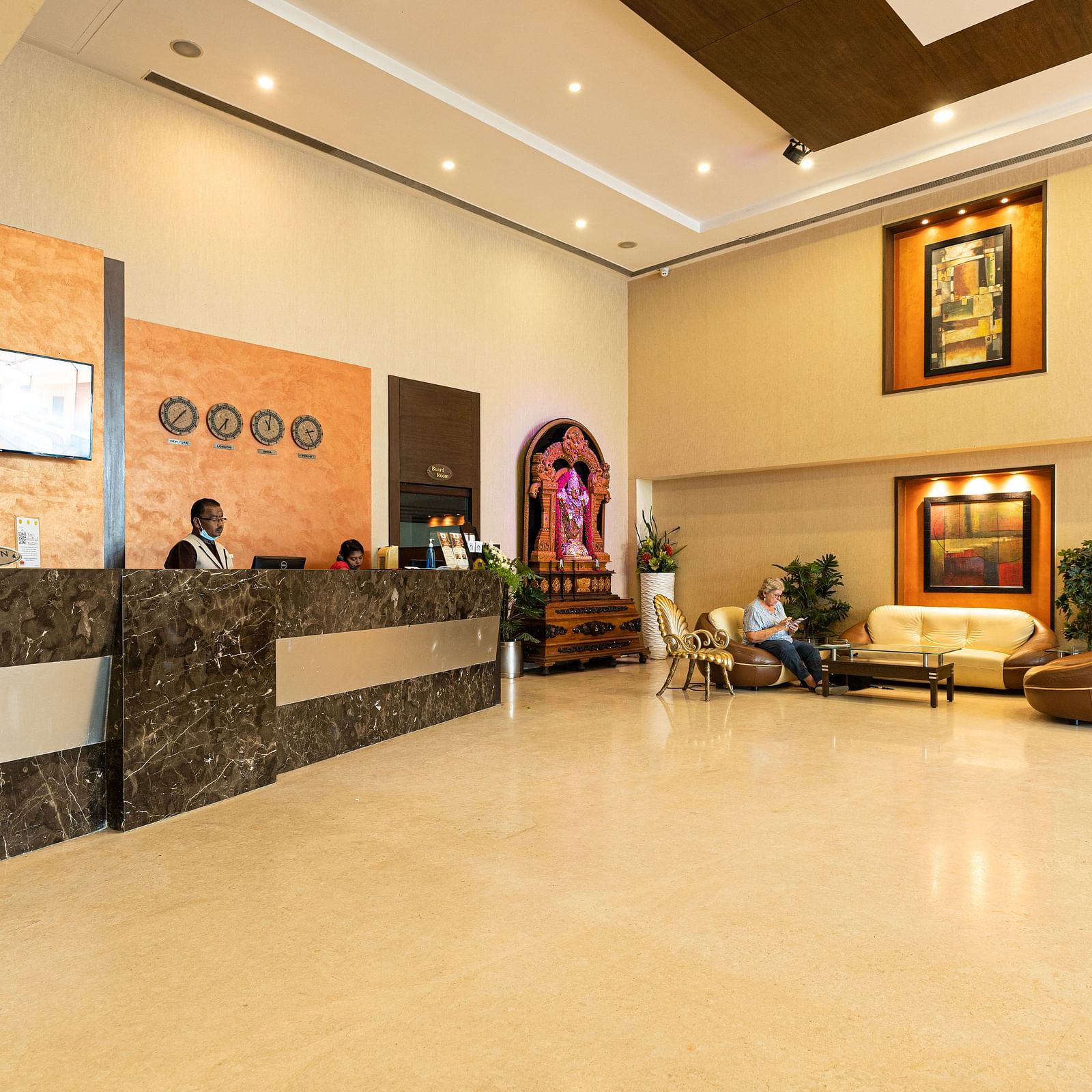 A reception area with people sitting behind the desk - Hotel Pai Vista, Mysore - Mysore Hotel Contact Number