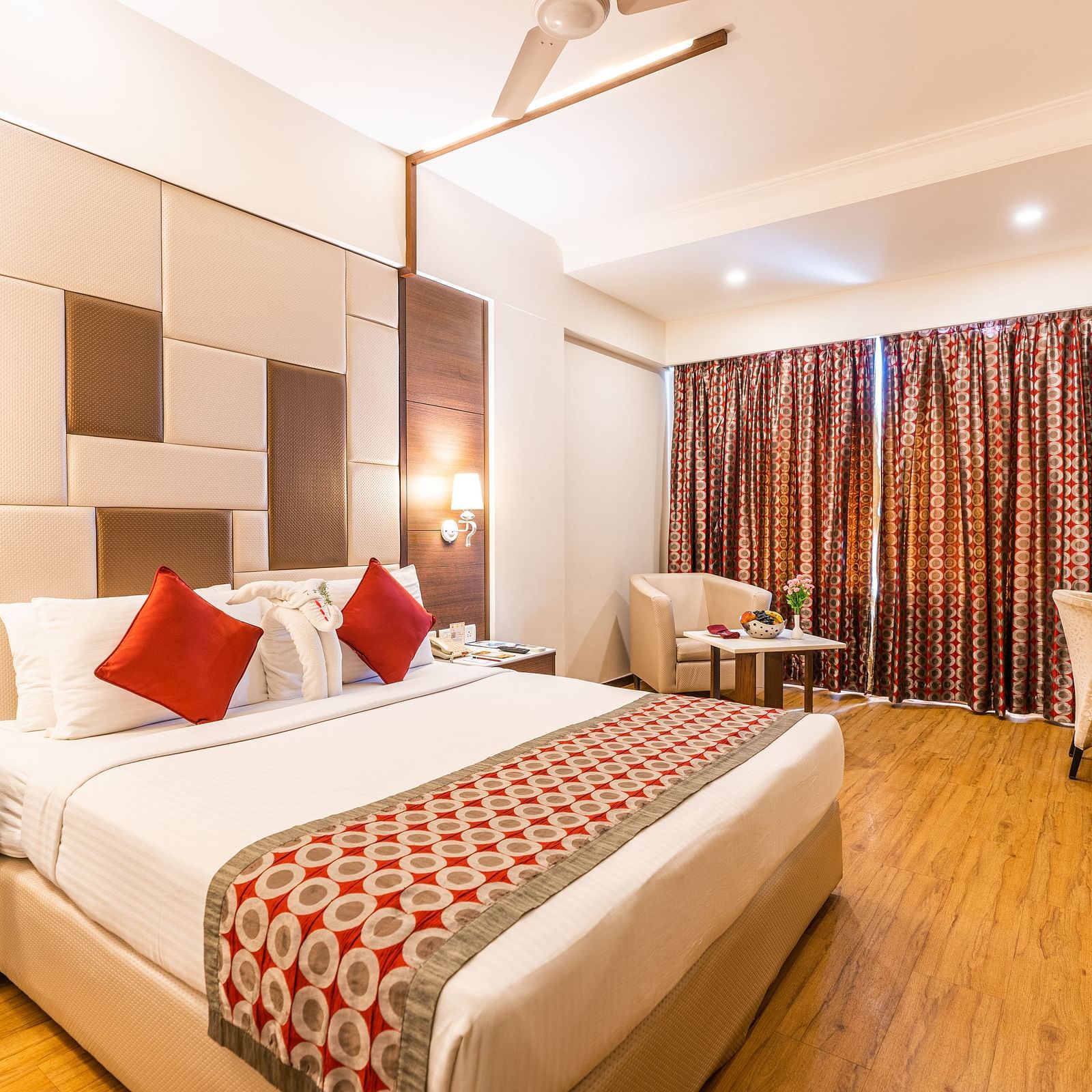 a double bed with side tables, lamps and sofa next to it inside one of the rooms - Hotel Pai Vista, Mysore