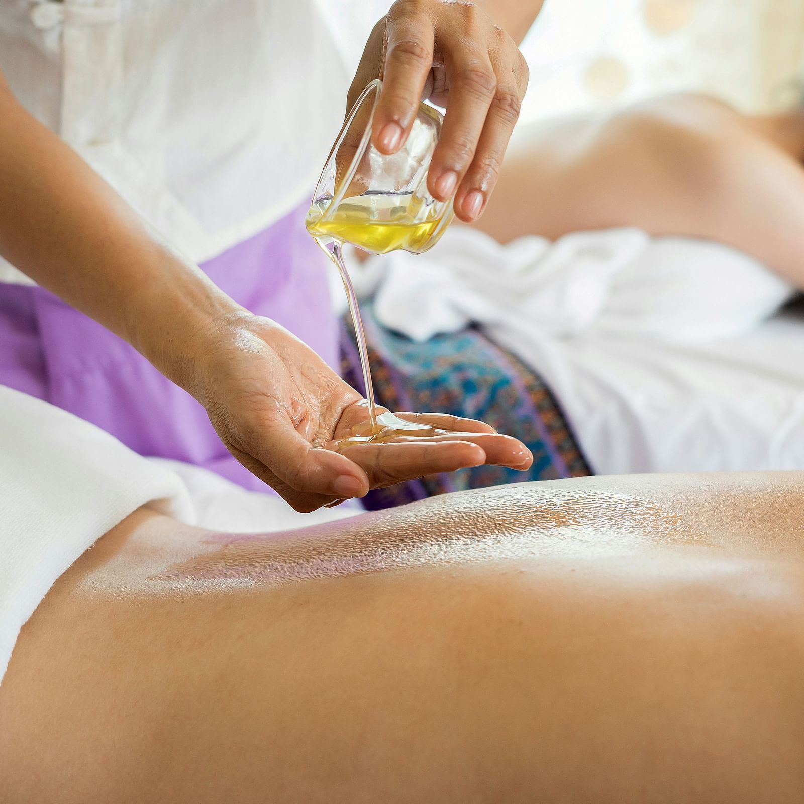 a woman applying oil on another woman's back