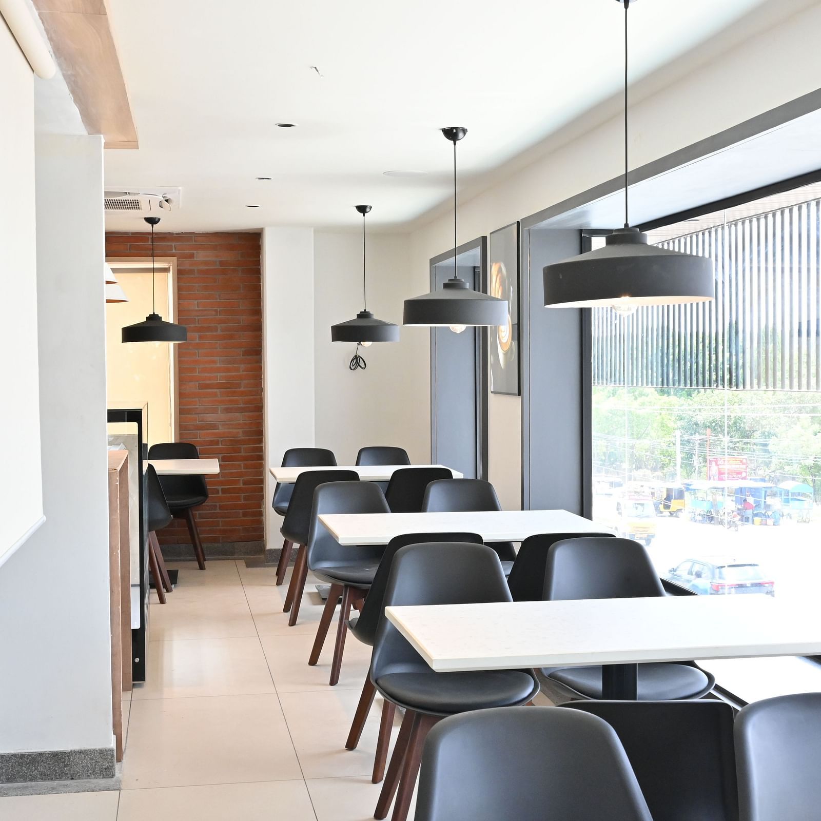 Image of coffee shop with chairs and lights hanging from the ceiling at Hotel Raai