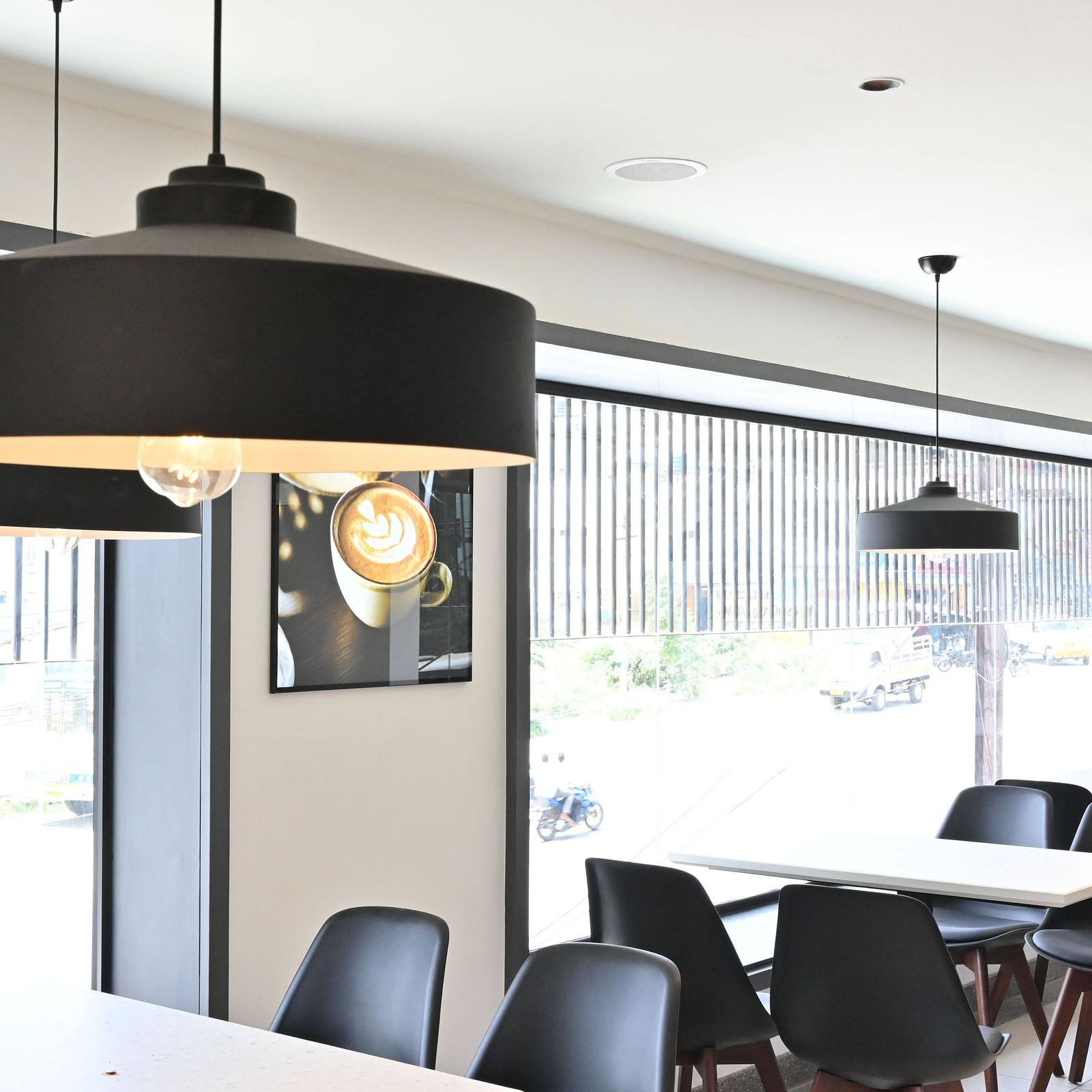 Side view of a coffee shop with chairs and lights hanging from the ceiling at Hotel Raai