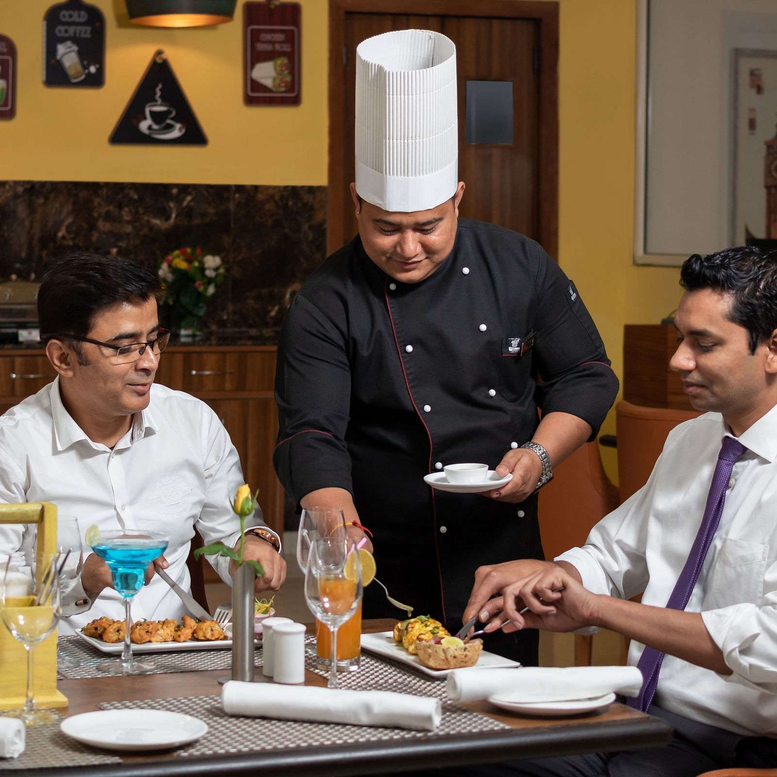 Image of a chef serving food to two people at Cafe Inde | Inde Hotel Cyber City