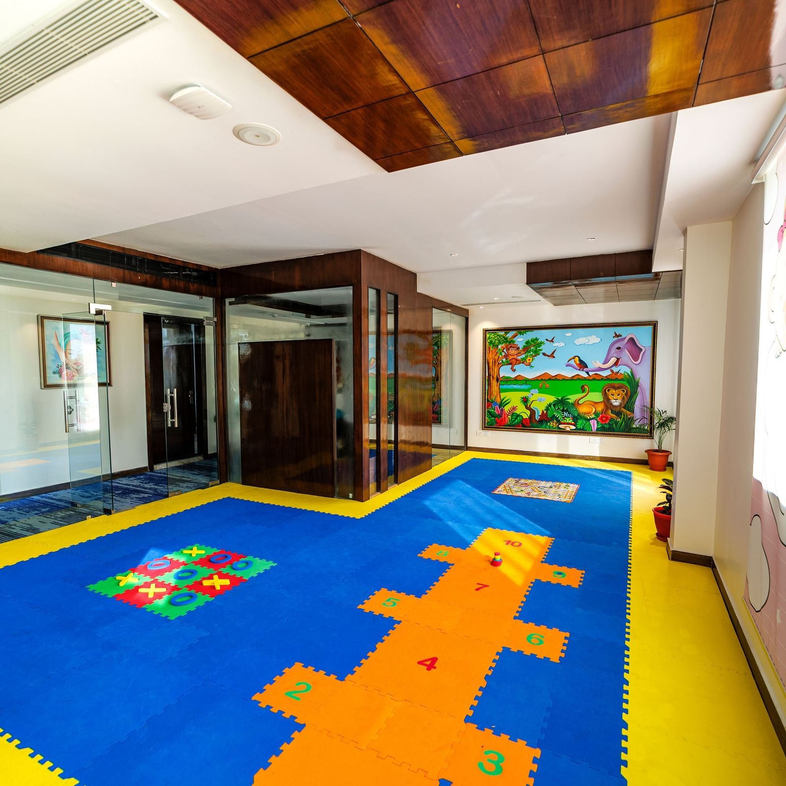 Children's playroom at Inde Reva Resorts Rishhikesh with colourful flooring, soft blocks, indoor lighting, and wall mural.