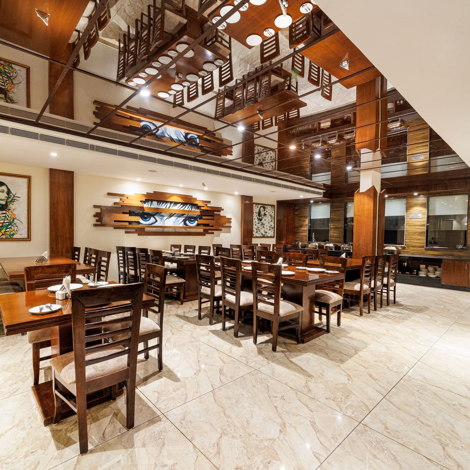 Restaurant at Inde Reva Resorts Rishhikesh featuring wooden furniture, open ceiling design, framed art, and tiled flooring.
