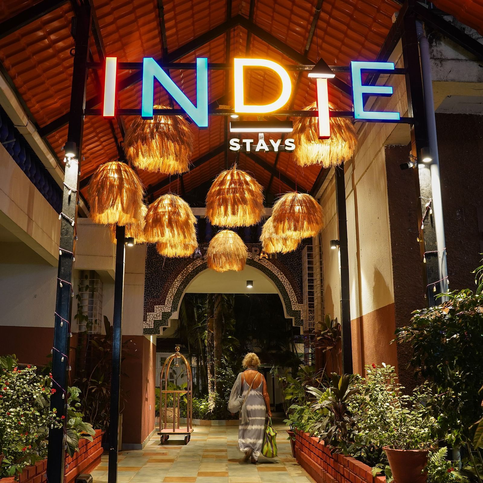 The entrance of Indie Stays features inviting hanging lights and plants on either side, creating a warm and welcoming atmosphere