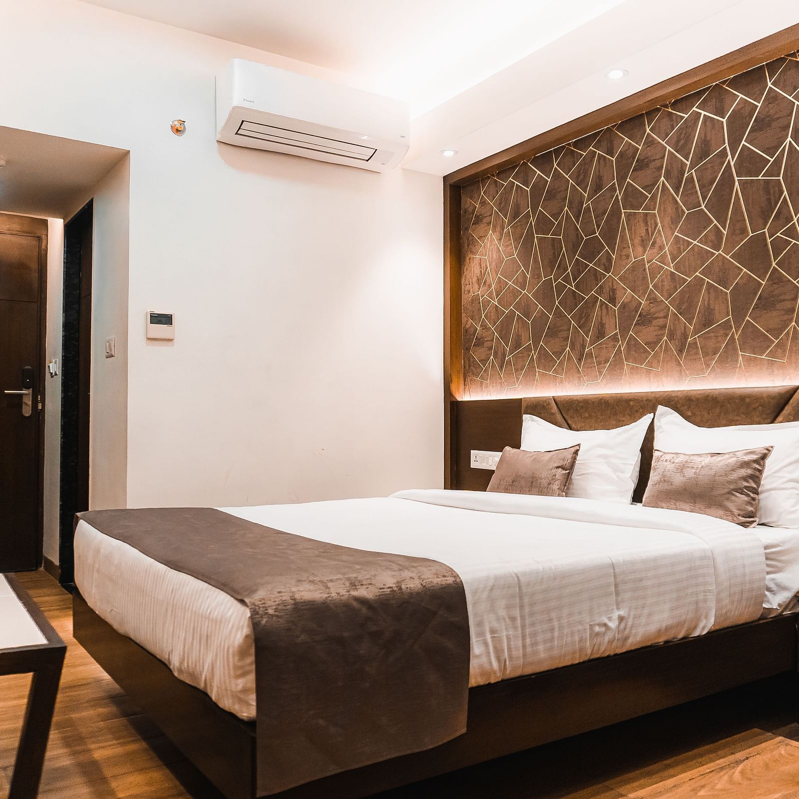 a bedroom with a large bed and side drawer and a table in front - Jardin Hotels