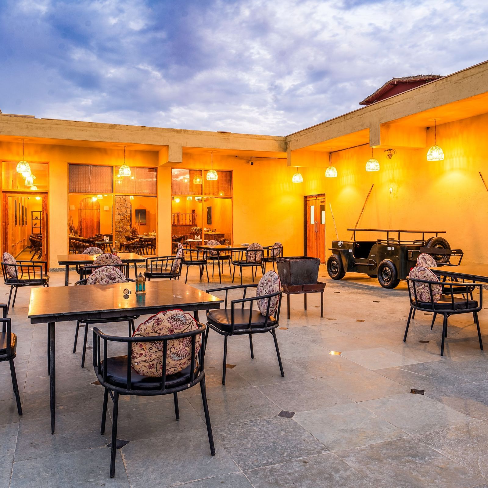 An image of rosettes restaurant featuring several lamps hanging from the roof and various sets of  tables and chairs are placed both indoor and outdoor at Kurja Jawai