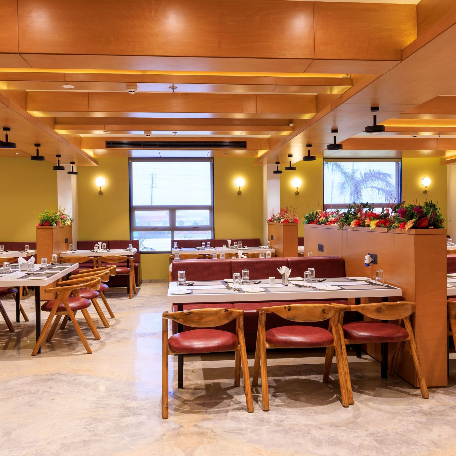 The well-lit restaurant at Lords Eco Inn Apple Gate features set tables with chairs, wooden accents, and natural light from windows.