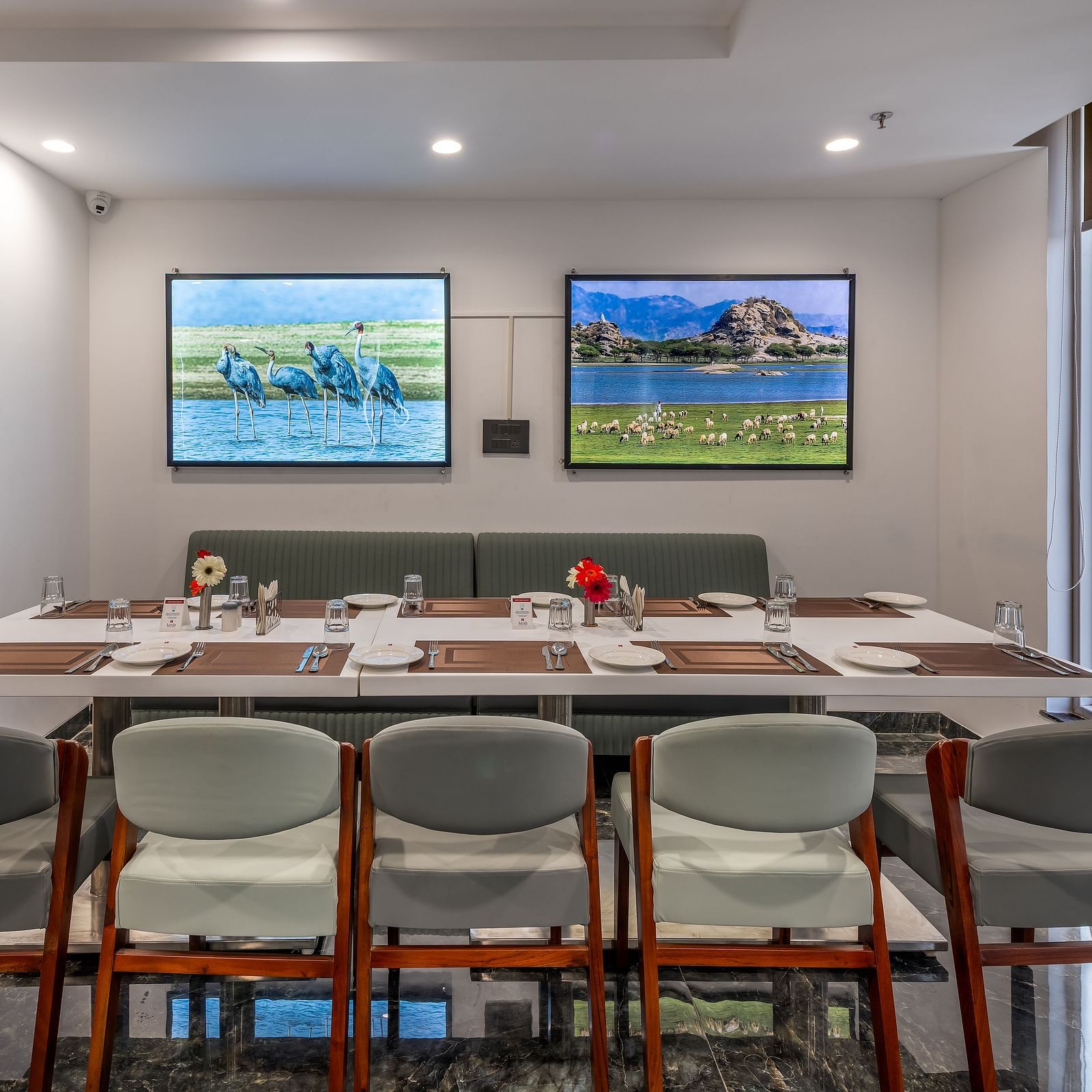 Modern dining area in BCR Resturant with cushioned seating, nature-themed wall art, large windows, and a neatly set table for a group meal