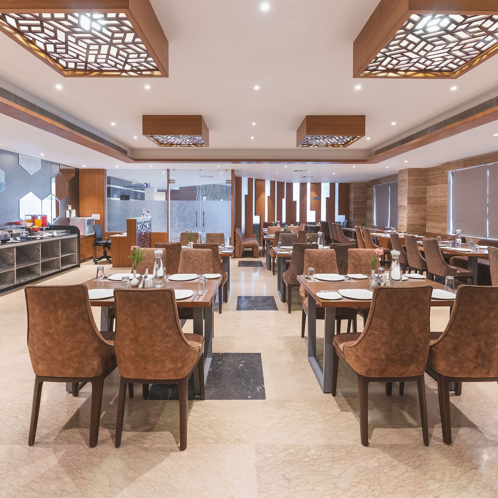 The spacious dining area at Lords Inn Udaipur is furnished with numerous tables and chairs, and features a buffet service along one wall.