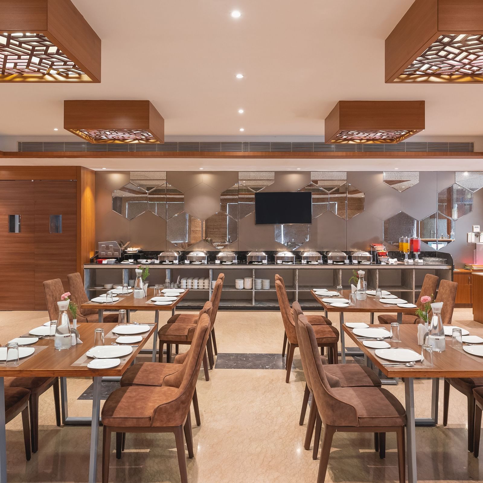 The spacious restaurant at Lords Inn Udaipur is set with multiple tables and chairs, featuring a buffet area in the background.