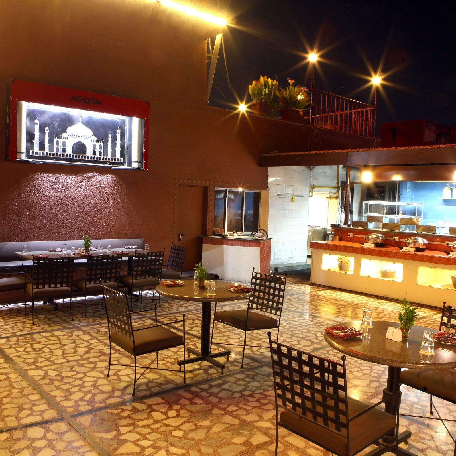A warmly lit dining or lounge area with tables and chairs at Lords Plaza Surat.