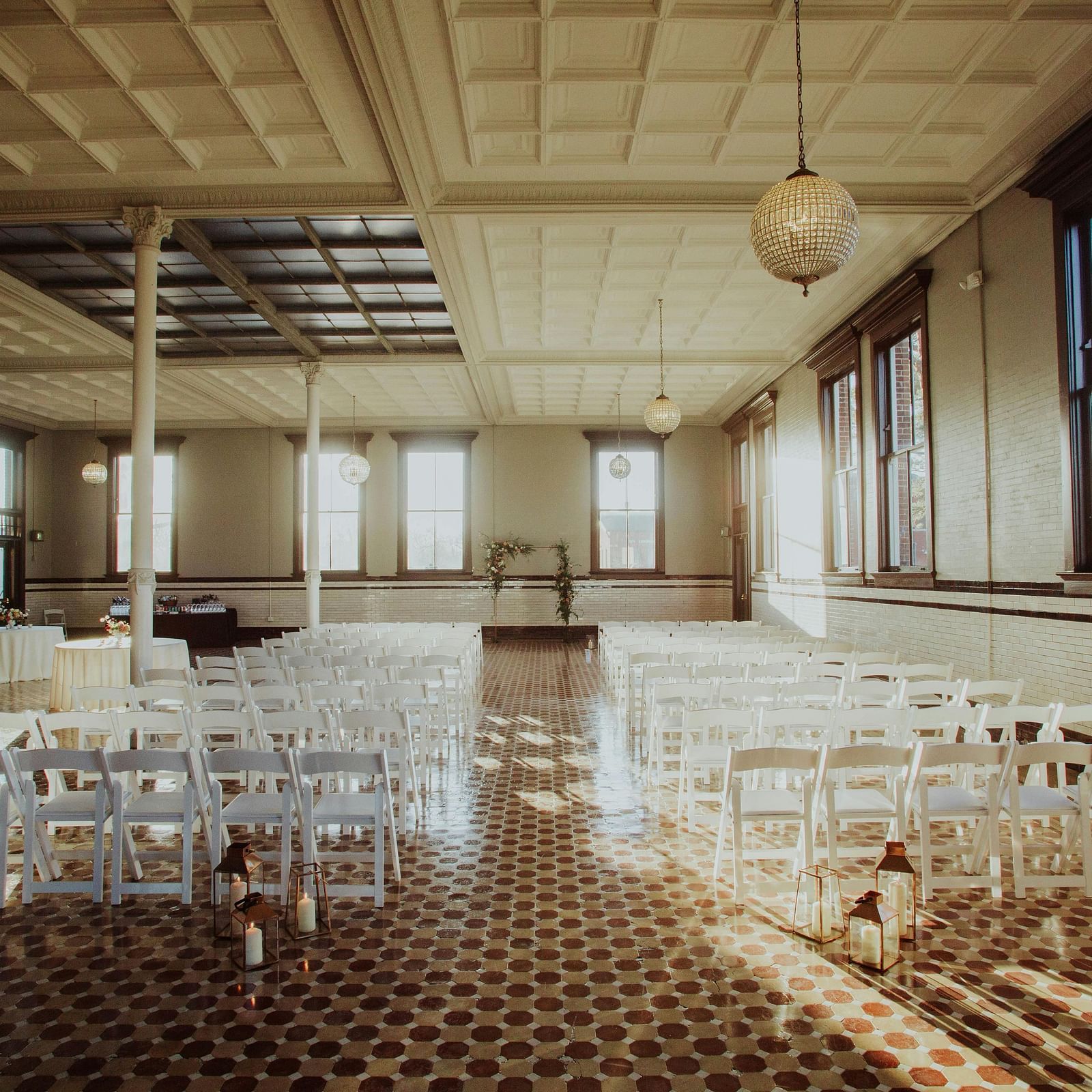 A spacious, empty hall with rows of tables and chairs ready for an event at Lords Plaza Surat.