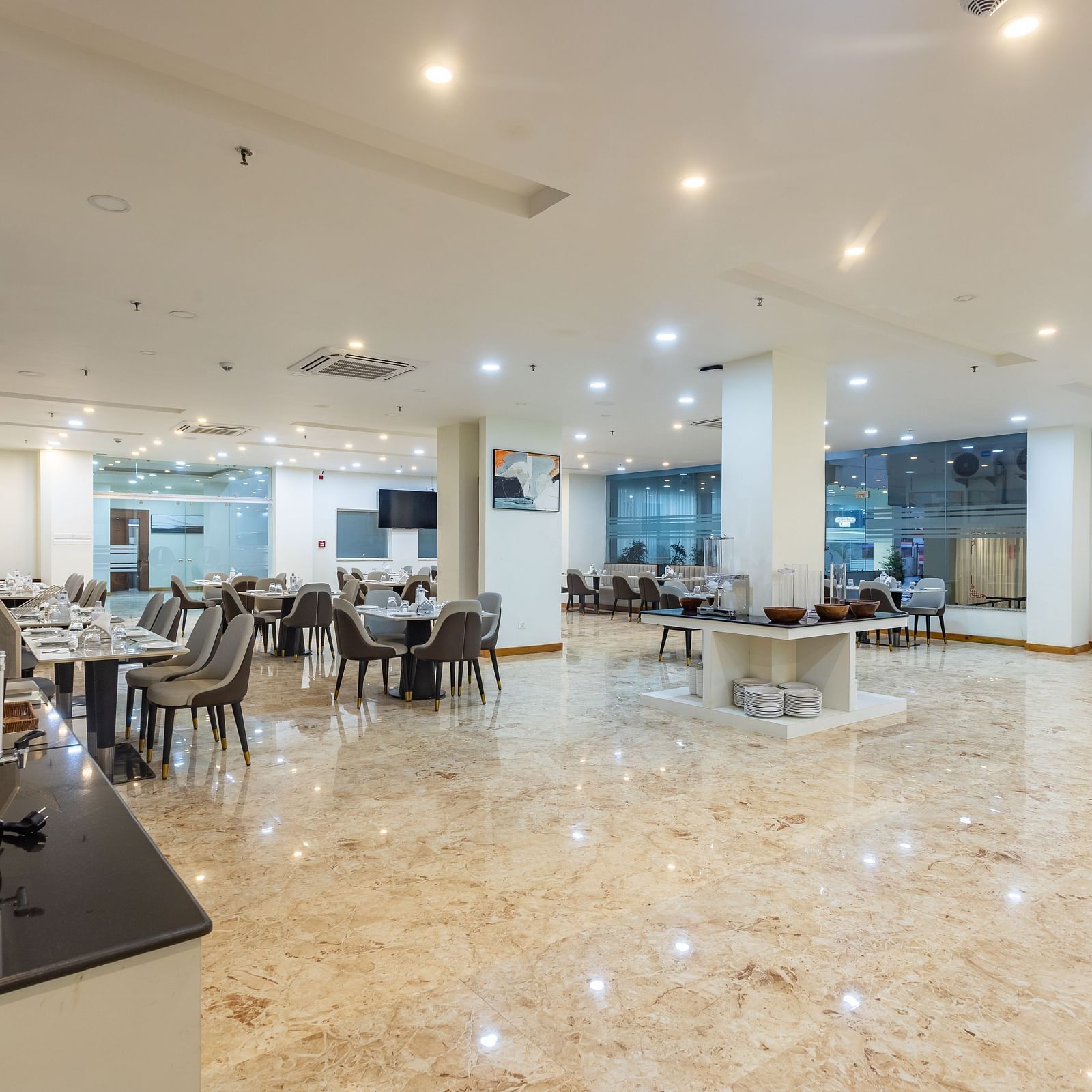 Extended view of the Blue Coriander Restaurant at Mandala Norling Lords Prime in Kathmandu featuring a buffet station and dining tables with neatly arranged cutlery.