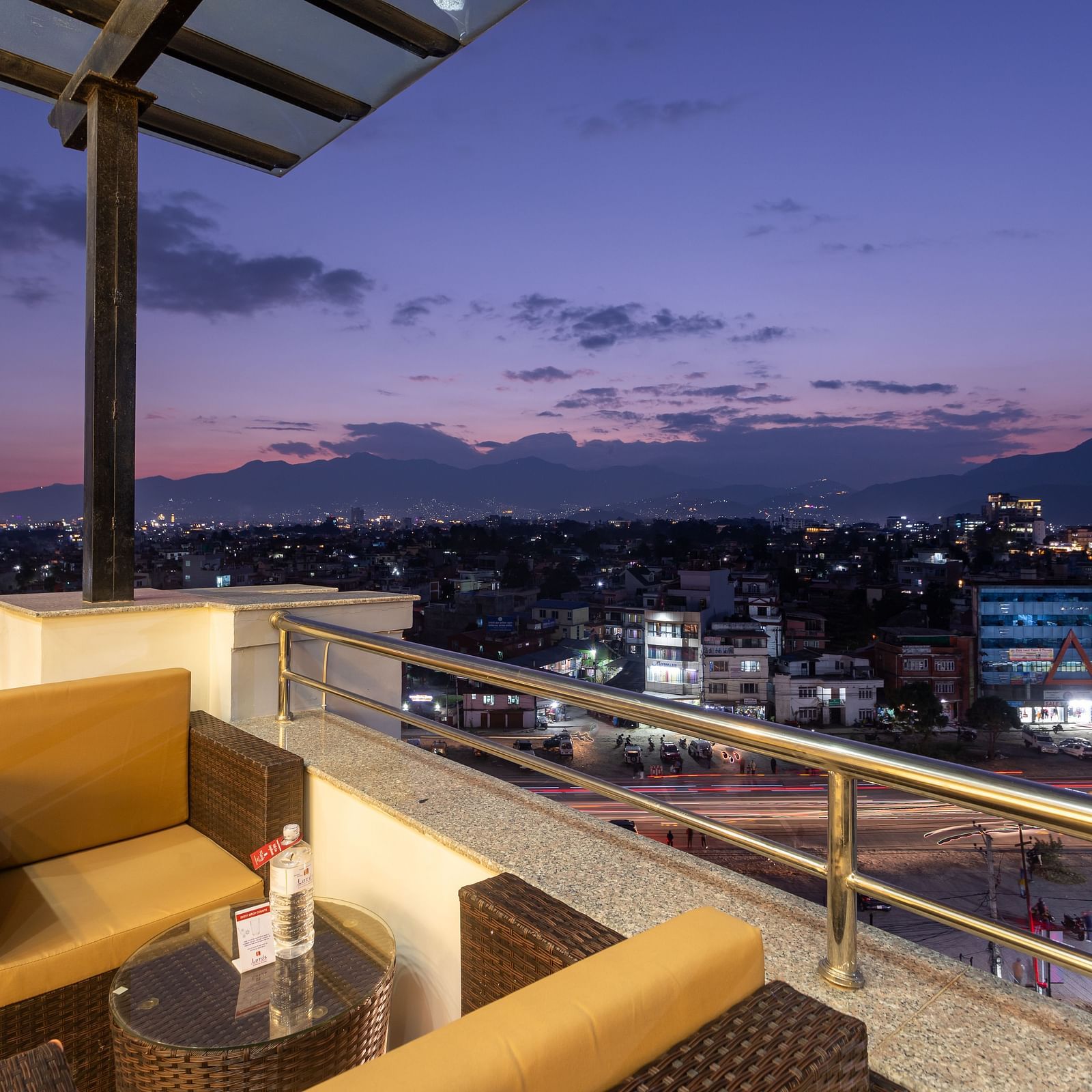 View of the purple and pink sky, urban and hilly landscape from an outdoors table at Mandala by Lords located in Mandala Norling Lords Prime, Kathmandu.