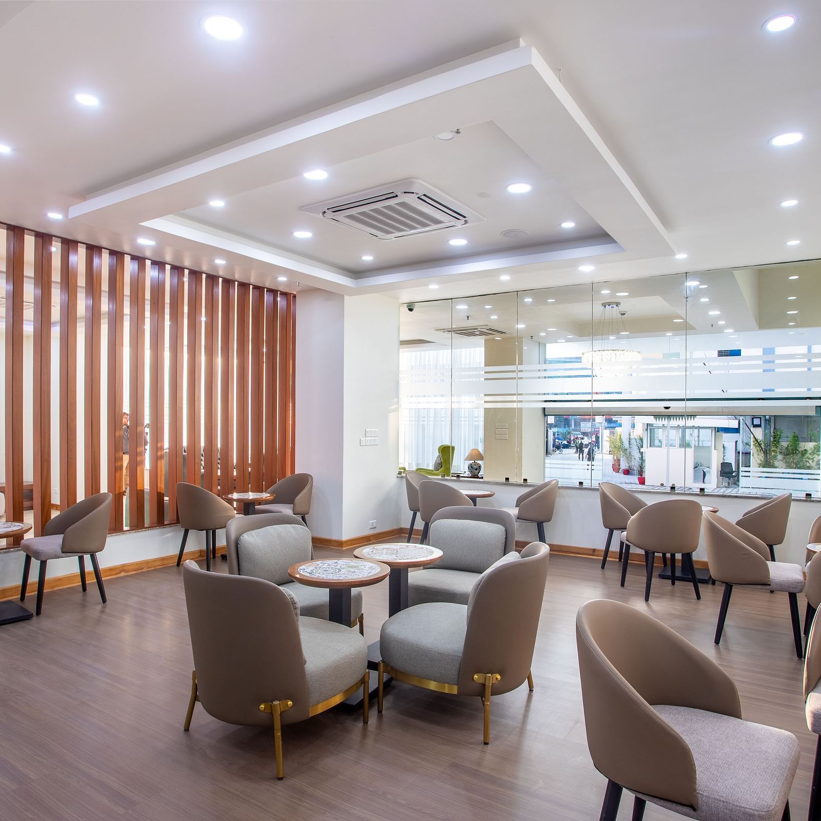 A coffee shop seating area with tables for four with ceiling lights and glass window