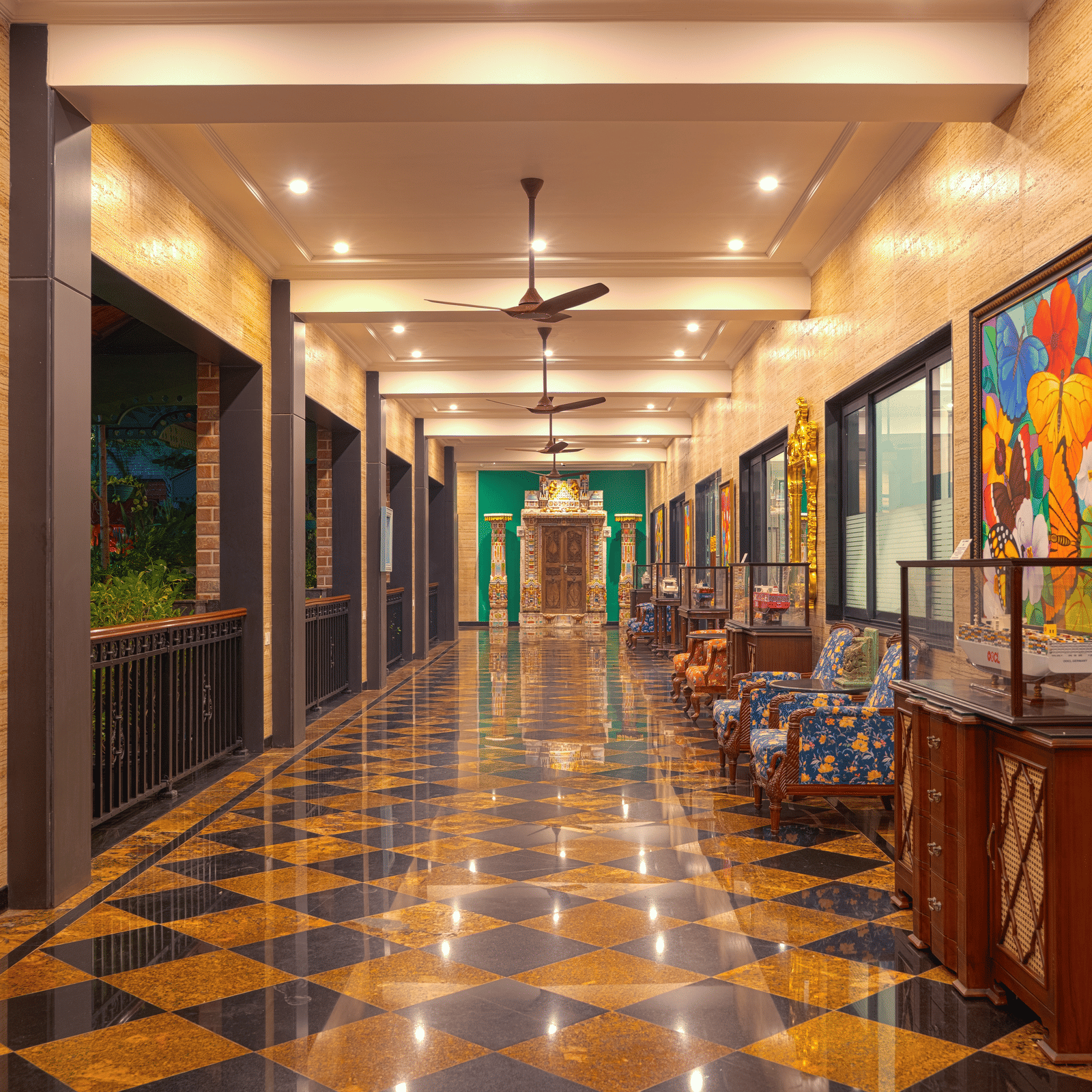A long, narrow corridor with a chequered floor, bright lighting, and abstract, colourful artwork hanging along the wall at MAYFAIR Bay Resort, Paradeep.